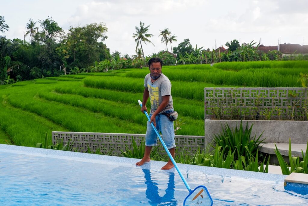 man in white polo shirt and blue denim jeans standing on swimming pool during daytime ievt175ndwo