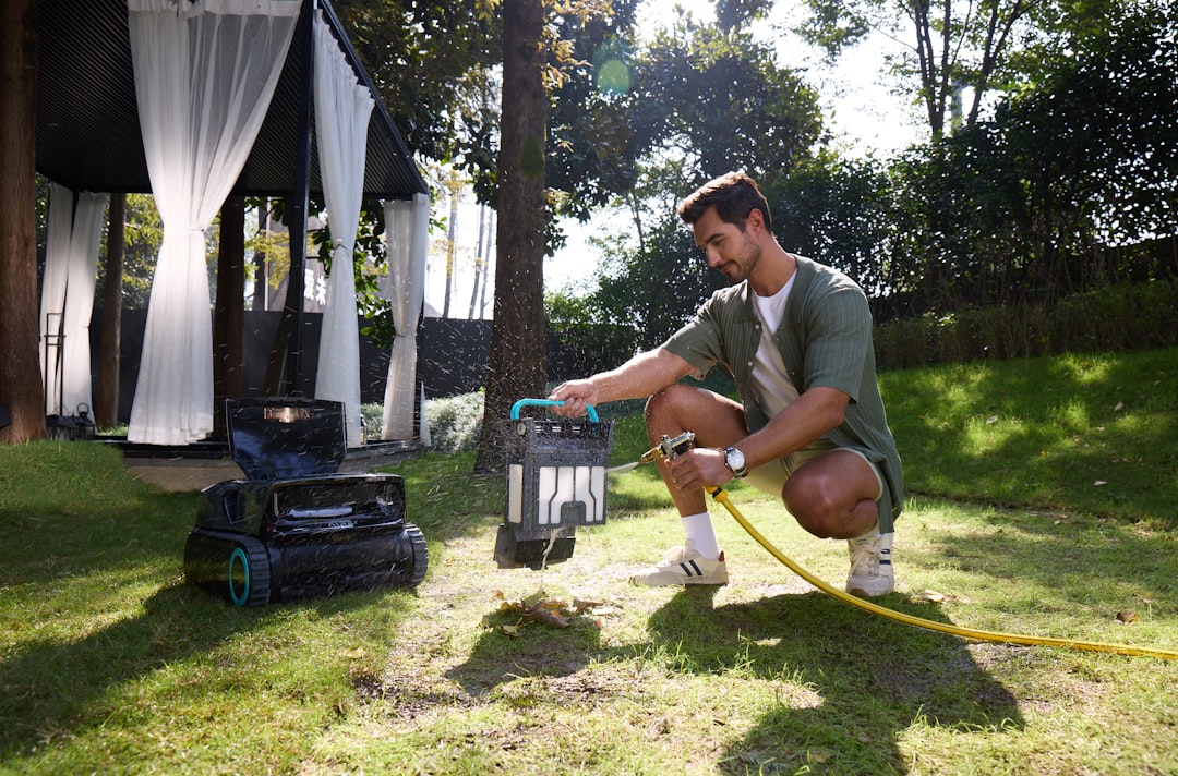 man watering a robotic lawnmower in a garden q19q6nez63e 1